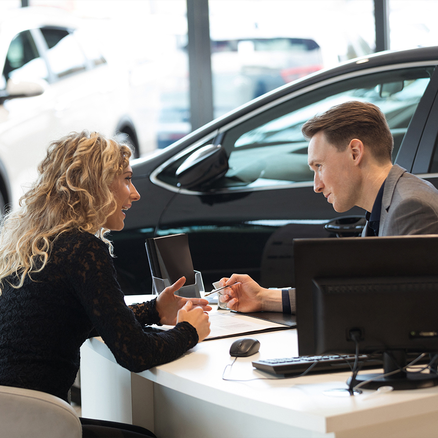 Happy female customer talking with salesman in showroom