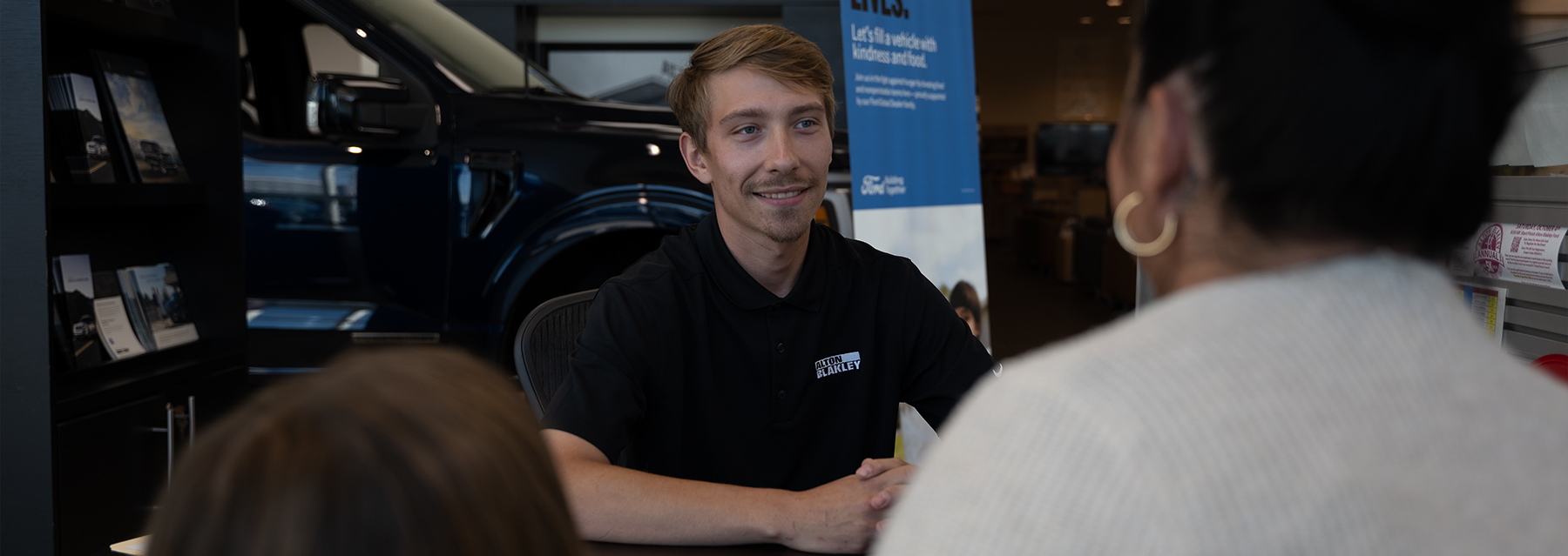 Dealership employee showing customers cars on showroom floor.