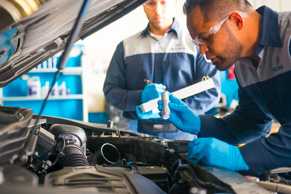 Acura technician working on engine of car