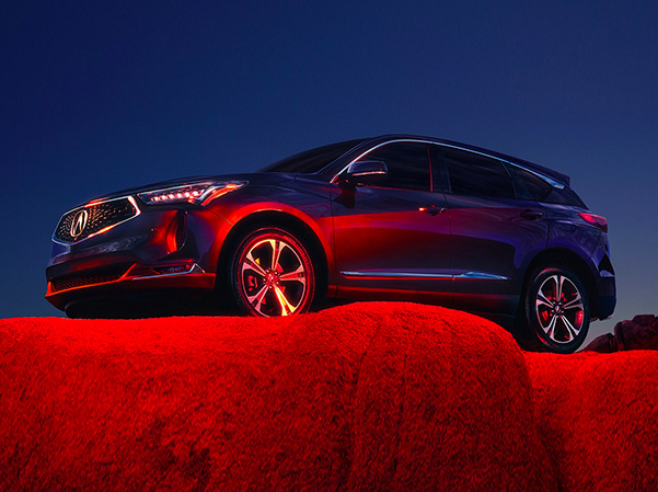 2022 Acura RDX parked on top of rock in red lighting.