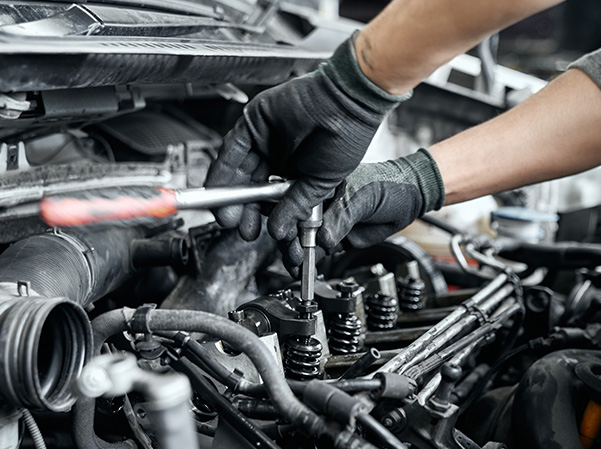 Closeup of technician working on engine of car in serviceroom.