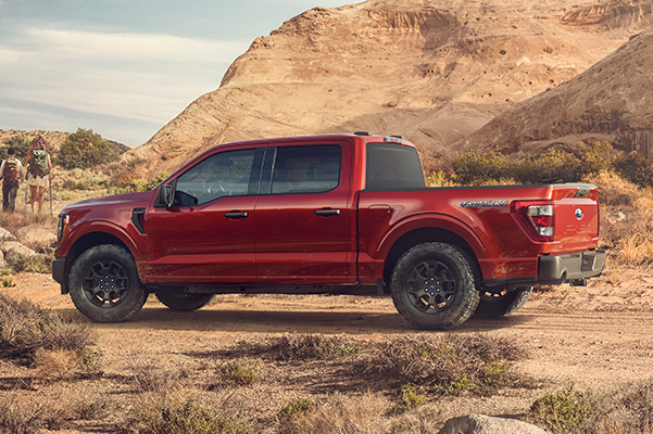 Side shot of 2023 Ford F-150 Rattler parked by red rocks.