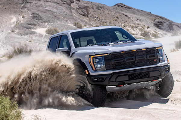 2023 Ford F-150 Raptor drifting through sand dunes.