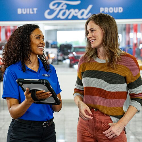 A customer has a friendly interaction with a Ford service representative at a Ford dealership.