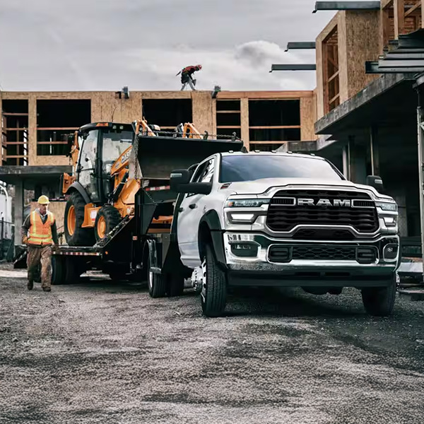 Head on shot of RAM truck towing heavy machinery