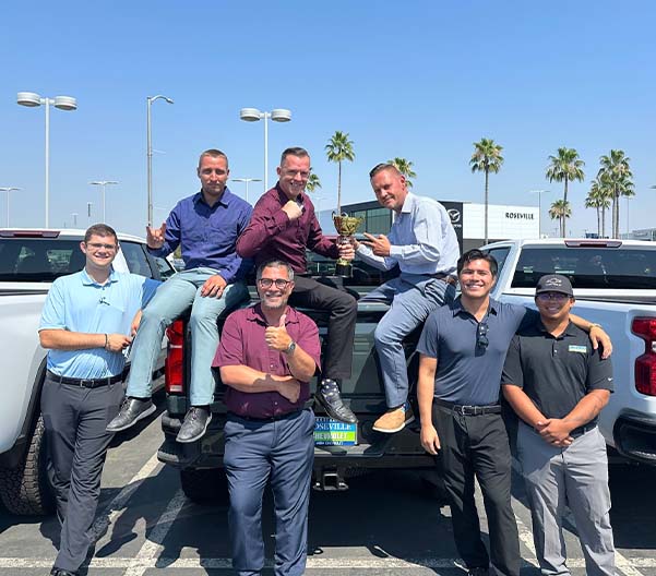 Dealership employee smiling shaking hands with satisfied customer.