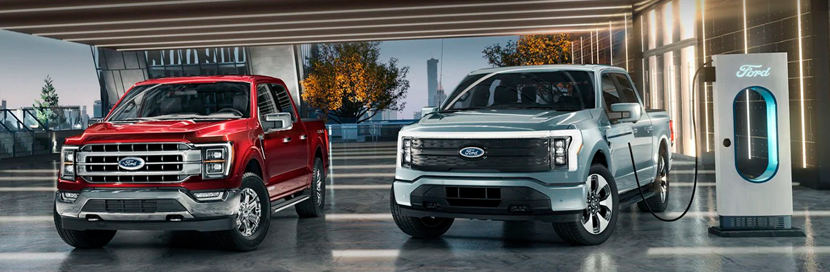 A ford super duty pickup next to a ford f 150 lightning that is charging